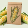 Kraft seed packet illustrated with Ambrosia Sweet Corn, with fresh Ambrosia Sweet Corn beside it