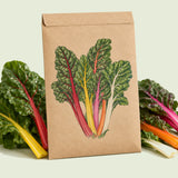 Kraft seed packet illustrated with Celebration Swiss Chard, with fresh Celebration Swiss Chard beside it