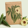 Kraft seed packet illustrated with Clemson Spineless 80 Green Okra, with fresh Clemson Spineless 80 Green Okra beside it
