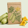 Kraft seed packet illustrated with Dirani Summer Squash, with fresh Dirani Summer Squash beside it
