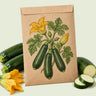 Kraft seed packet illustrated with Emerald Delight Summer Squash, with fresh Emerald Delight Summer Squash beside it