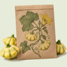Kraft seed packet illustrated with Gelber Englischer Patty Pan Squash, with fresh Gelber Englischer Patty Pan Squash beside it
