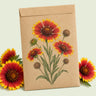 Kraft seed packet illustrated with Goblin Gaillardia, with fresh Goblin Gaillardia beside it