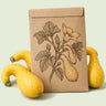Kraft seed packet illustrated with Golden Crookneck Summer Squash, with fresh Golden Crookneck Summer Squash beside it