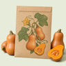 Kraft seed packet illustrated with Honeynut Mini Butternut Squash, with fresh Honeynut Mini Butternut Squash beside it
