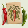 Kraft seed packet illustrated with Joe E Parker Anaheim Pepper, with fresh Joe E Parker Anaheim Pepper beside it