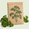 Kraft seed packet illustrated with Moss Curled Parsley, with fresh Moss Curled Parsley beside it