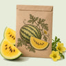 Kraft seed packet illustrated with Mountain Sweet Yellow Watermelon, with fresh Mountain Sweet Yellow Watermelon beside it
