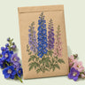 Kraft seed packet illustrated with Pacific Giants Delphinium Blend, with fresh Pacific Giants Delphinium Blend beside it